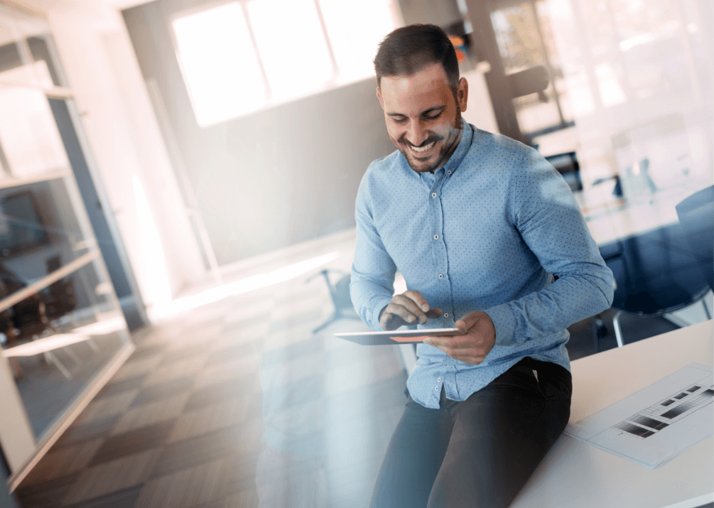 man sitting on a desk looking at a tablet