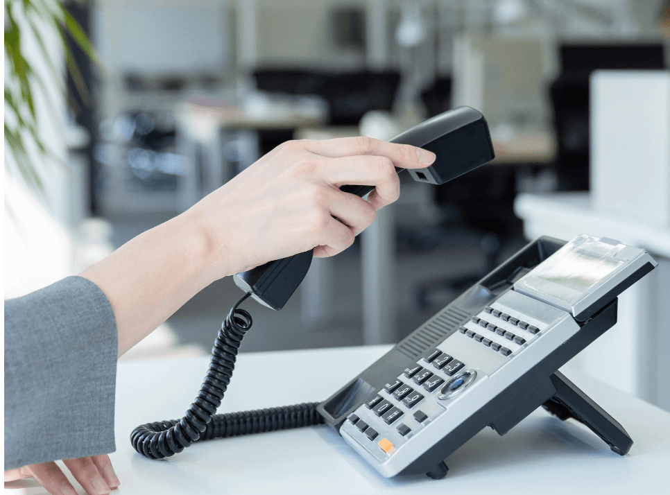 A pair of hands connecting a wire to a telephone handset.