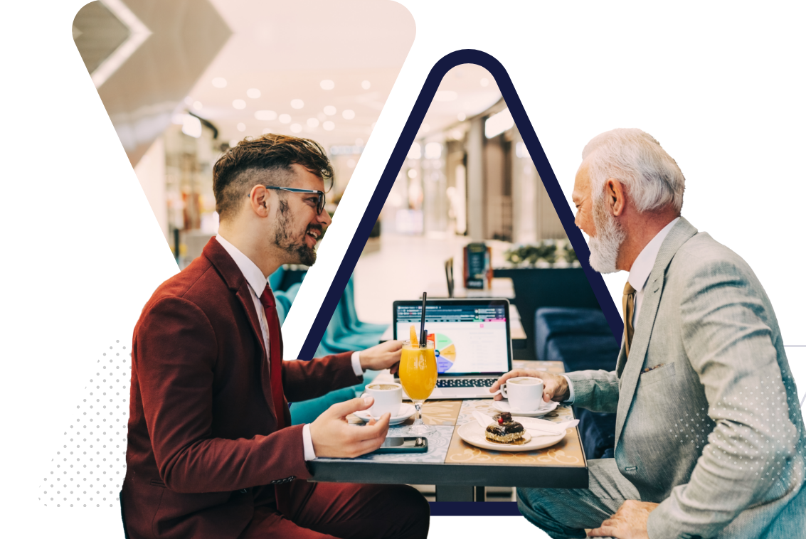 two men sitting in a cafe looking at a laptop