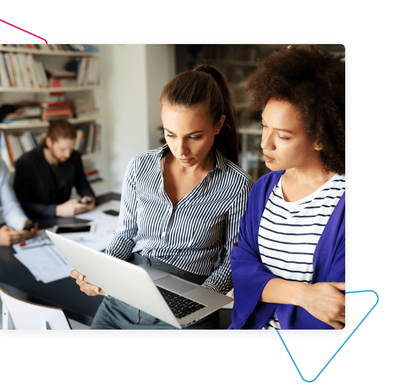 a woman showing another woman something on a laptop