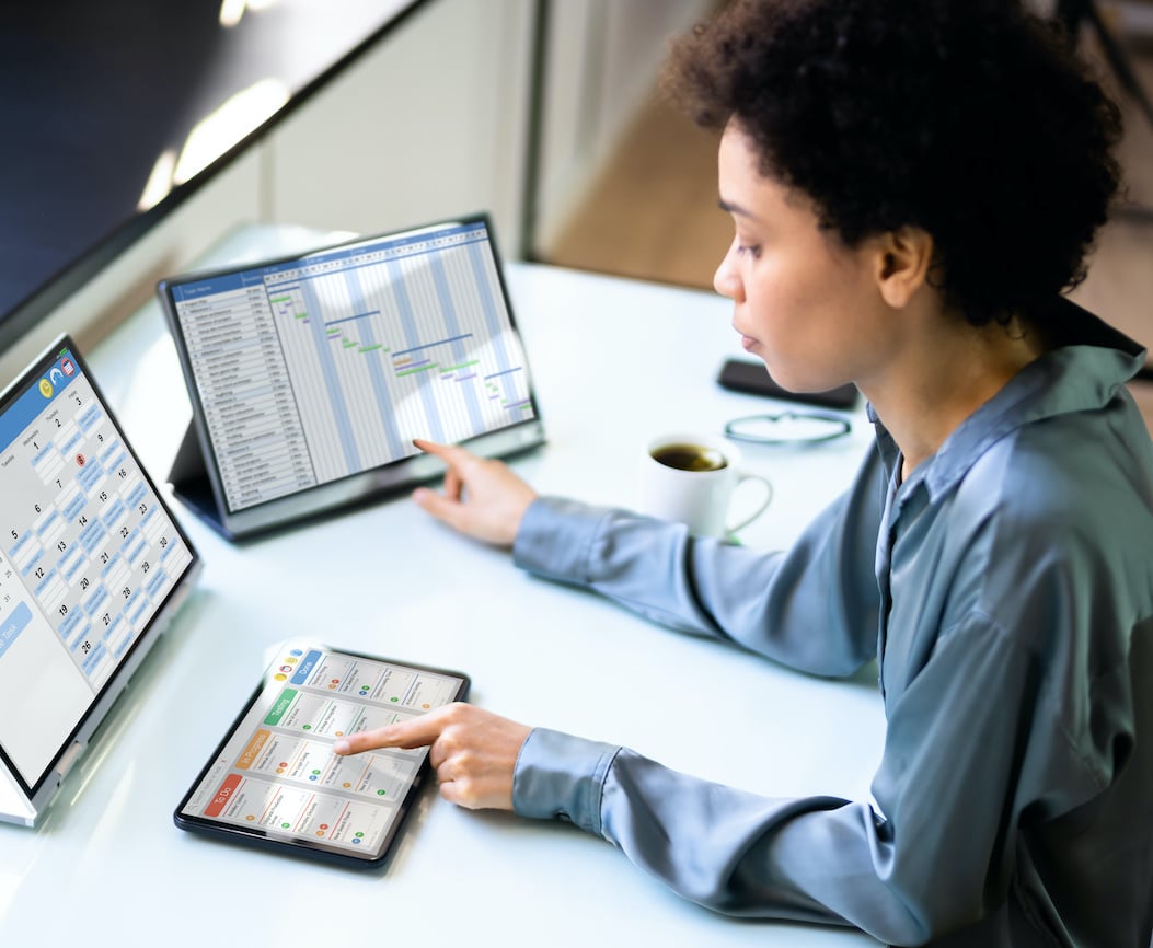 woman looking at three tablets