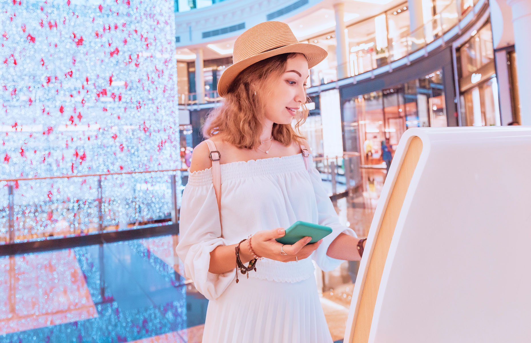 A woman inside a shopping centre touching an interactive screen.