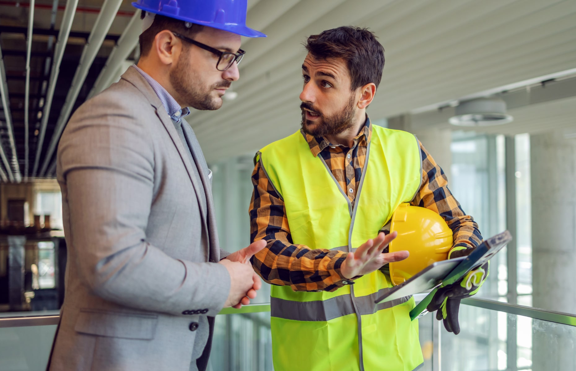 Two men on a construction site looking at a tablet.